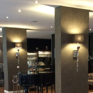 Ein modernes Interieur mit Wandlampen, Tischen und Stühlen in einem dunklen, stilvollen Raum.