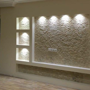 Eine Wand mit einer Mosaikverkleidung aus kleinen Steinen und integrierten LED-Spotlights.