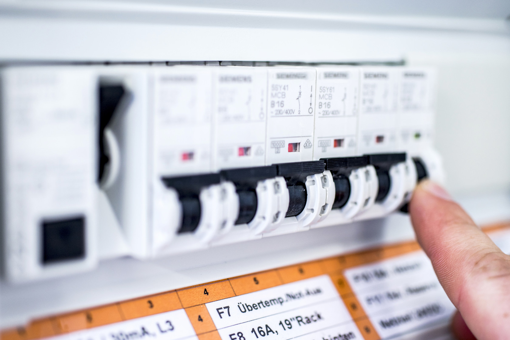 Eine Hand drückt einen Schalter in einem elektrischen Sicherungskasten.