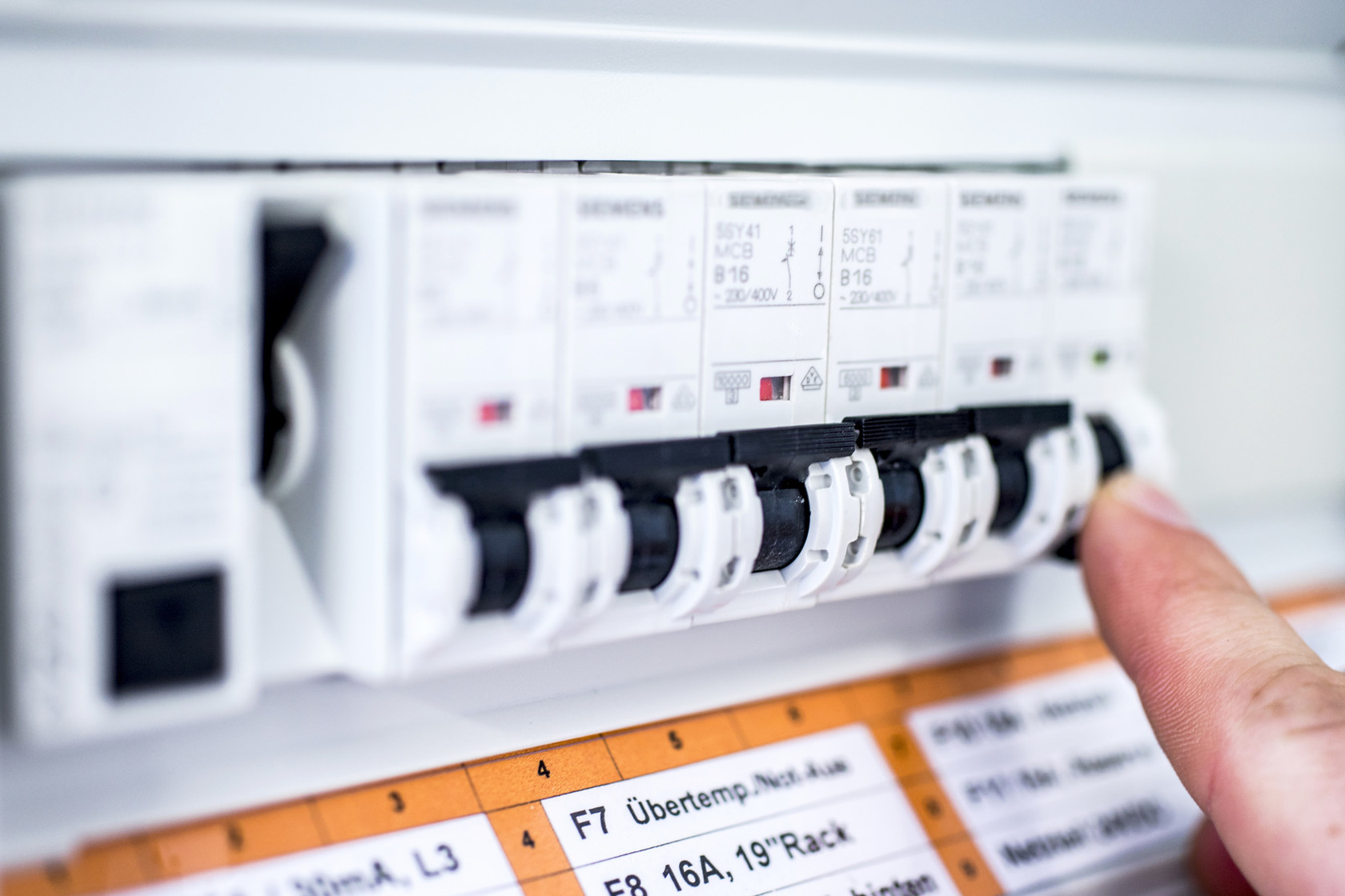 Eine Hand drückt einen Schalter in einem elektrischen Sicherungskasten.